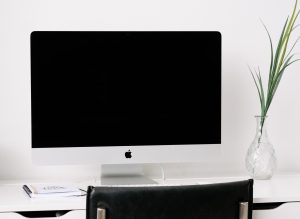 iMac in a home office with white walls and a black chair